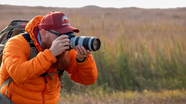 A person using a camera with a large lens to take a photo.