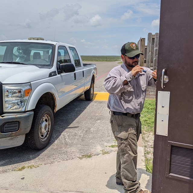 A park maintenance worker fixing a door. 