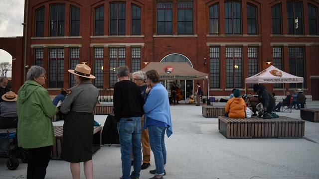 Small group talking to a park ranger in front of a large historic building