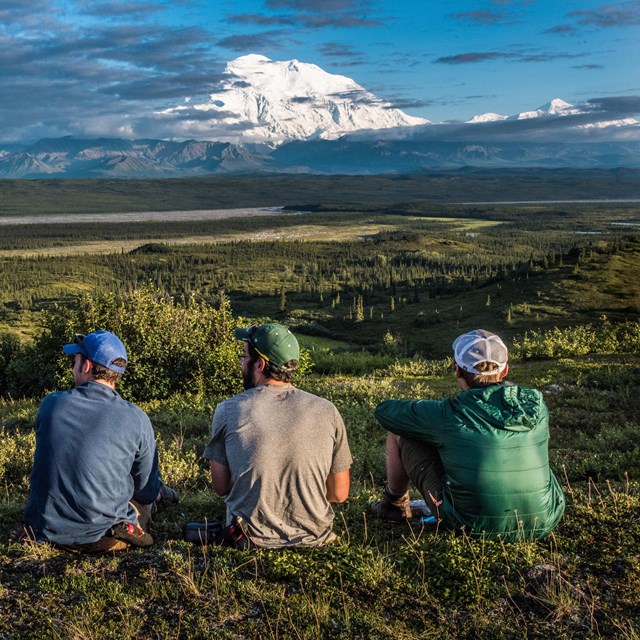 Campers sitting in a prairie with a very tall mountain in the distance