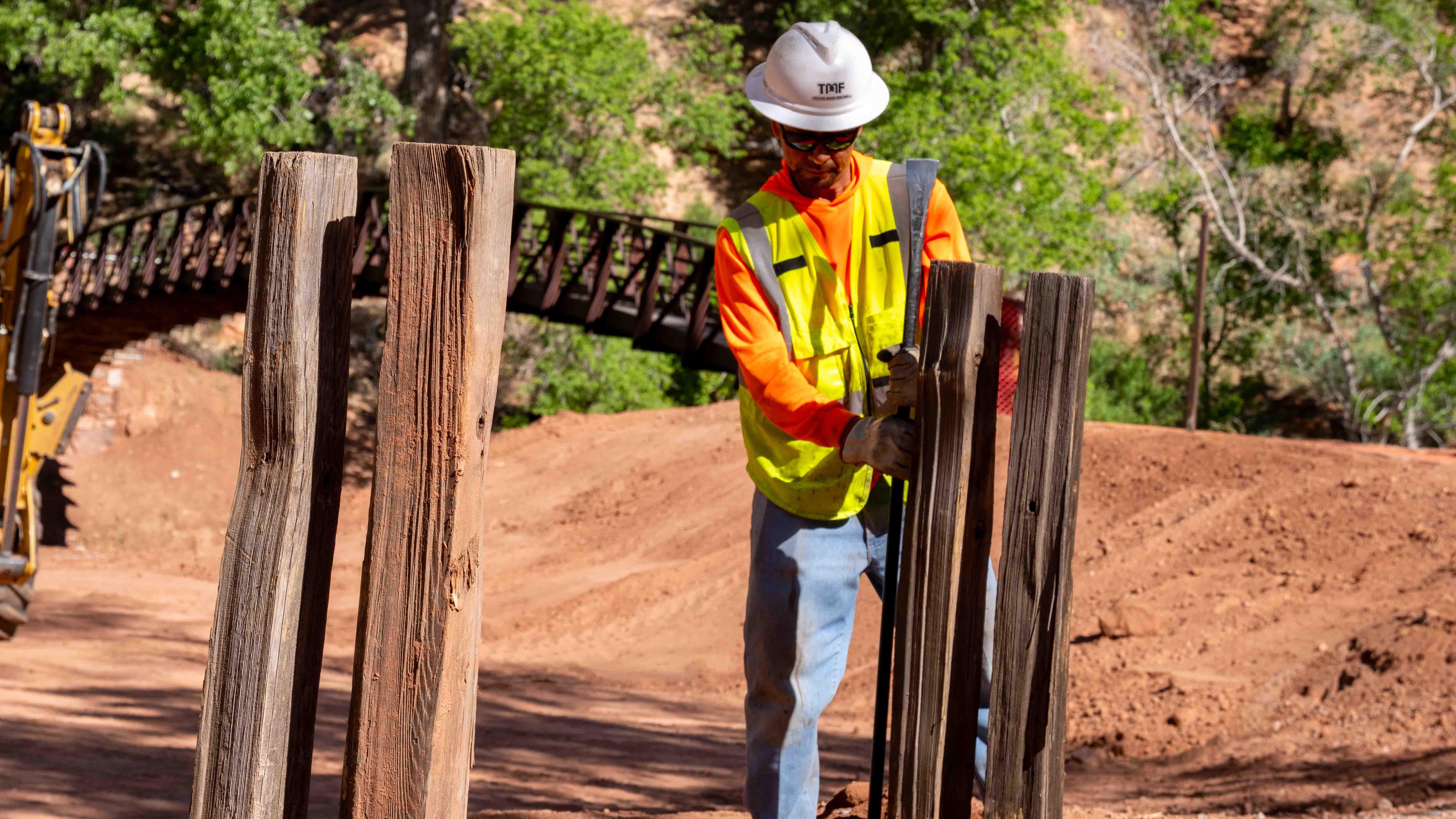 A construction worker installing a wooden fence.