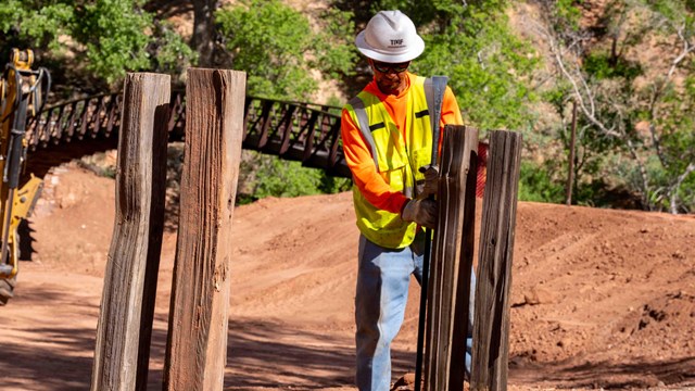 A construction worker installing a wooden fence.