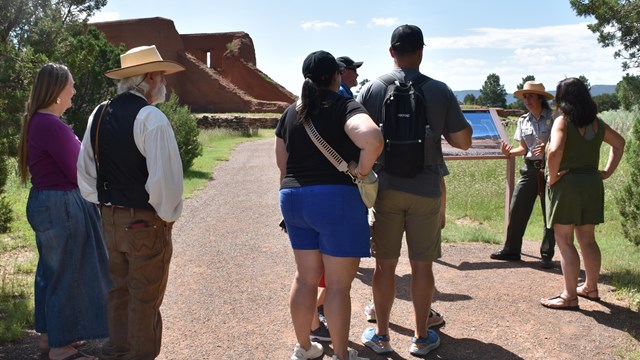 A ranger gestures to a group in front of the Pecos mission church