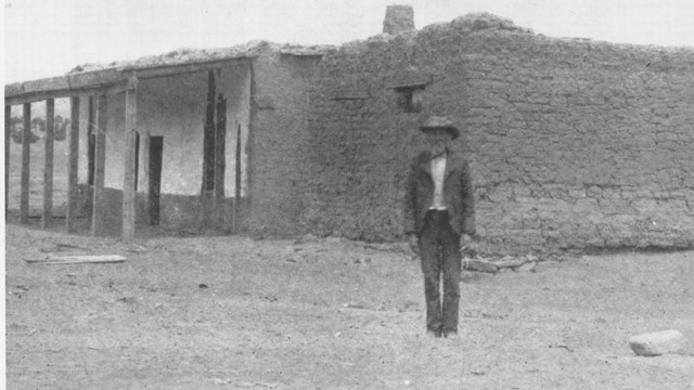 Historic photo of Martin Kozlowski in front of small unadorned adobe building