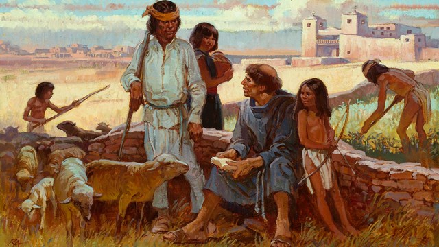 Friar sitting on low wall with indigenous people in front of church and pueblo