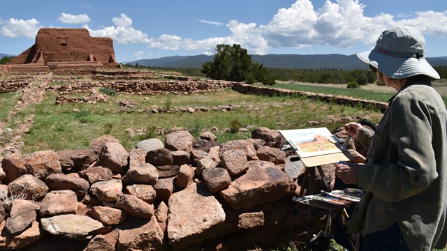Artist painting in front of adobe mission church