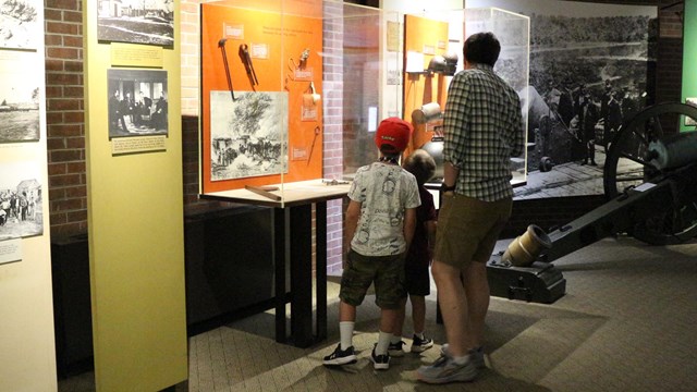 A white male and two children look at exhibits.