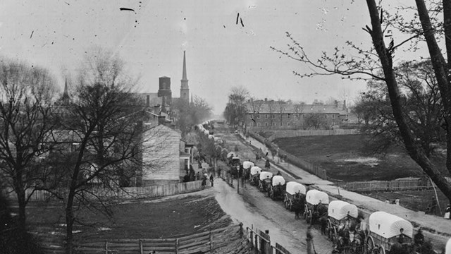 Photo: A long line of wagons moving into a town.