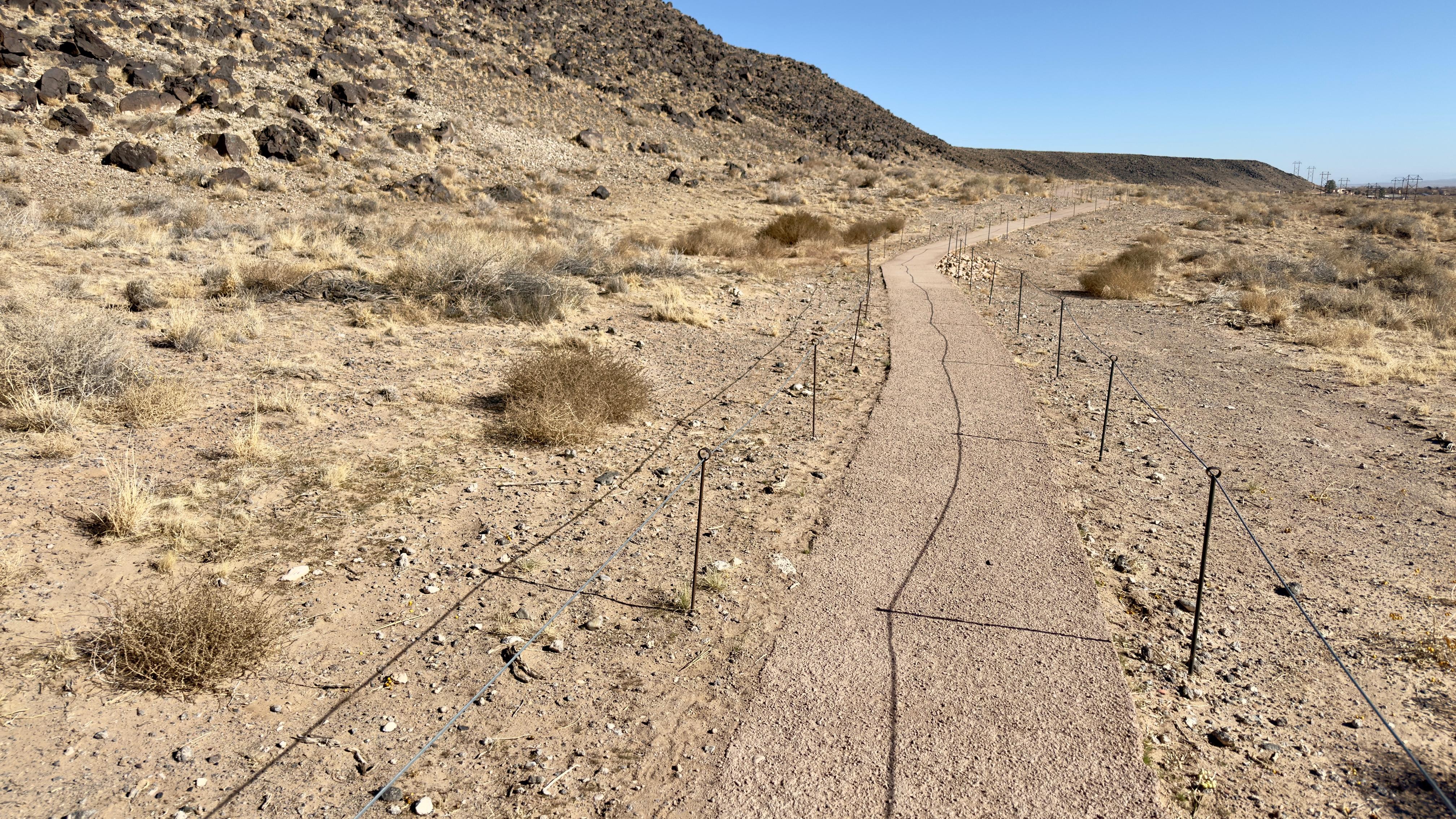 A trail surrounded by cables through a sandy volcanic landscape.