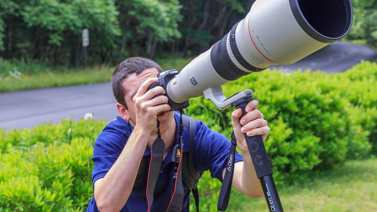 Man looking through camera with very large lens