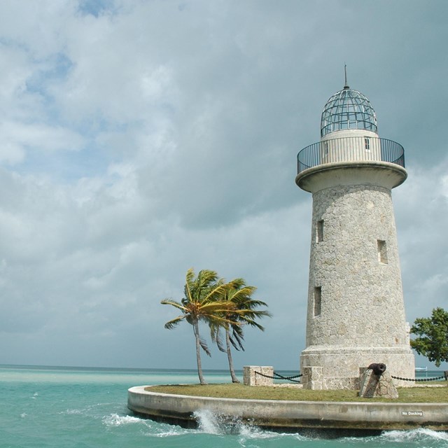 green tropical water on left with lighthouse and palm trees on rights