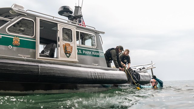 A Park Ranger assists with getting someone out of the water and onto a boat.
