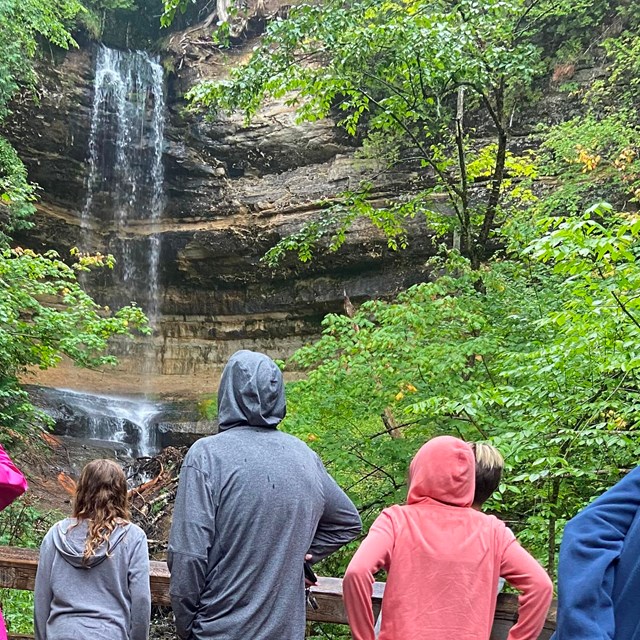People on a wet wood platform looking at a waterfall