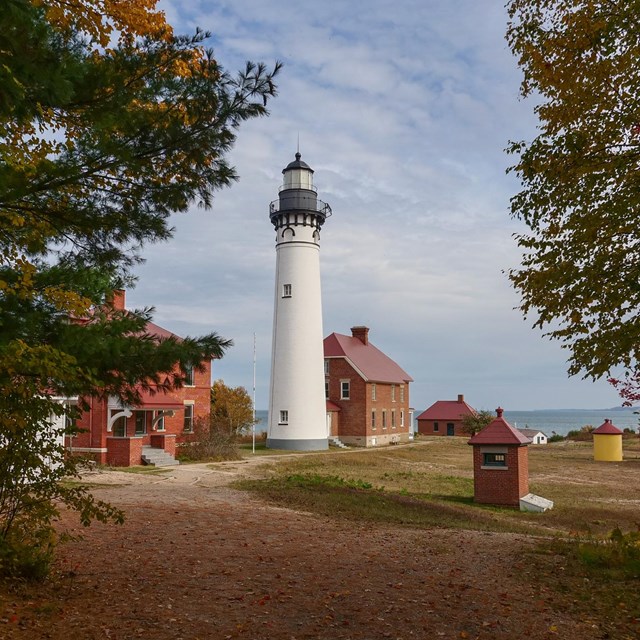 A tall, white lighthouse surrounded by red brick buildings