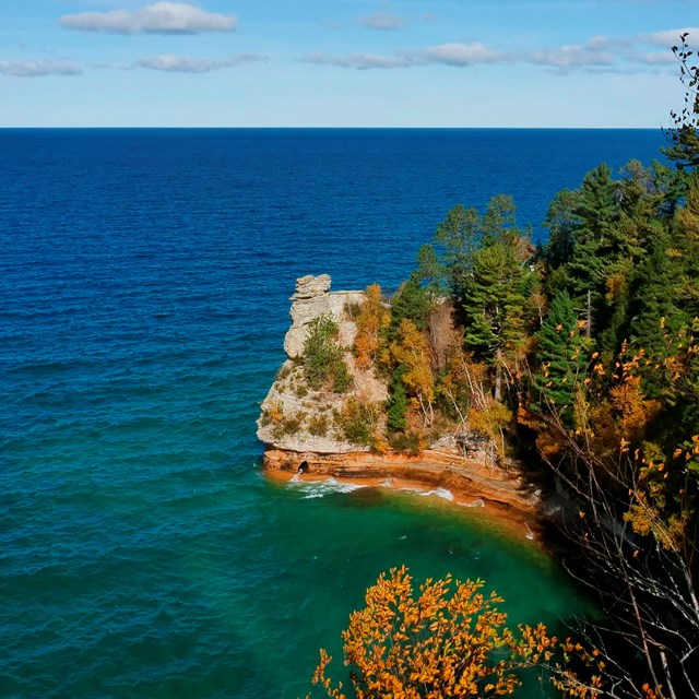 A sandstone rock formation rises out of Lake Superior