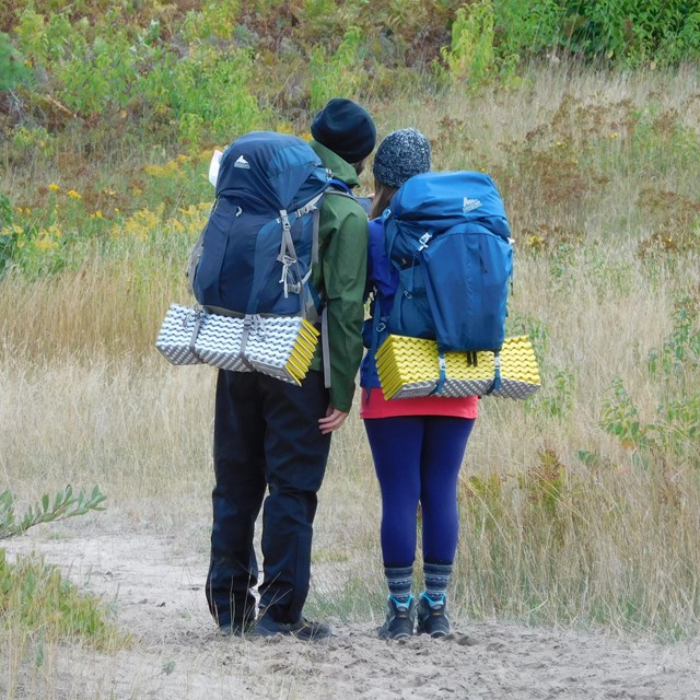 Two hikers check a map on a hiking trail