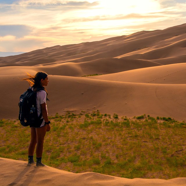 Kid standing near sand dunes at sunset