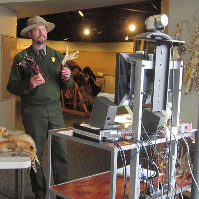 Ranger holding up props to a computer with a webcam