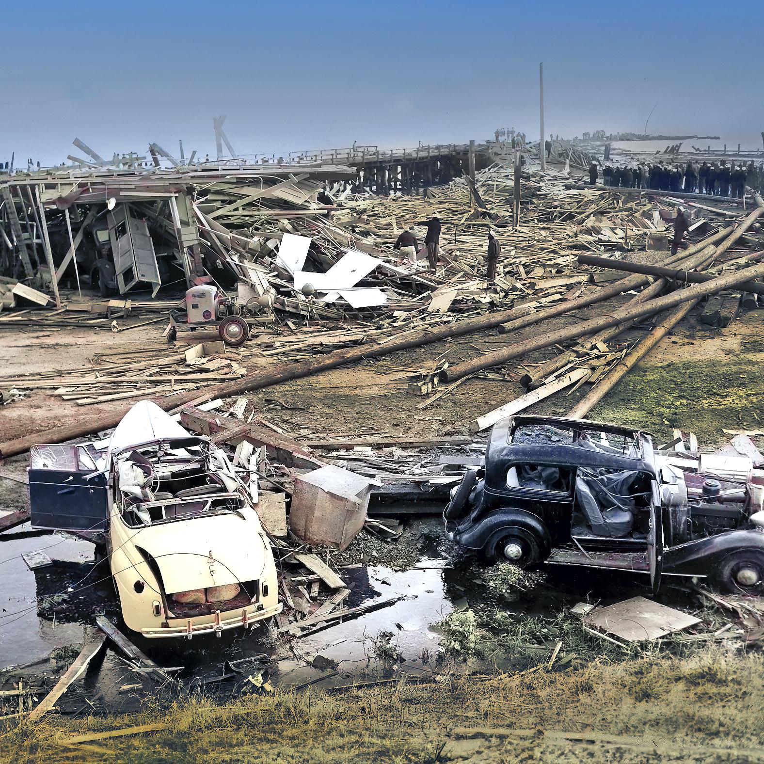 A colorized historic photo of the disaster aftermath which shows a lot of wooden debris and vehicles