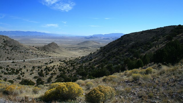 A desert canyon leading out onto a vast desert landscape.
