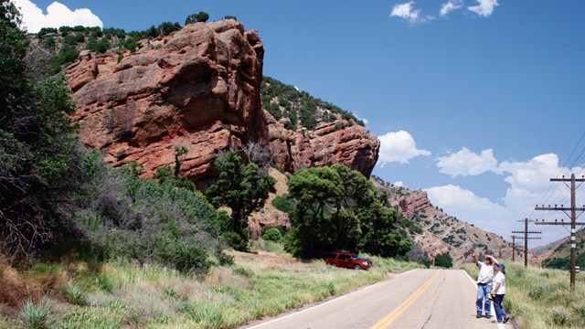 A road leads through a steep, red-walled canyon.