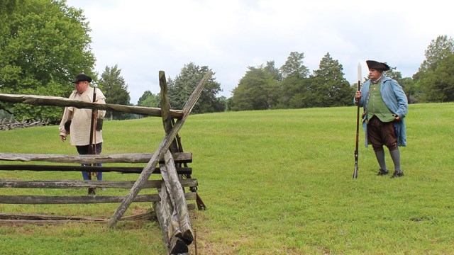 Two men in Revolutionary War attire doing a rifle demonstration