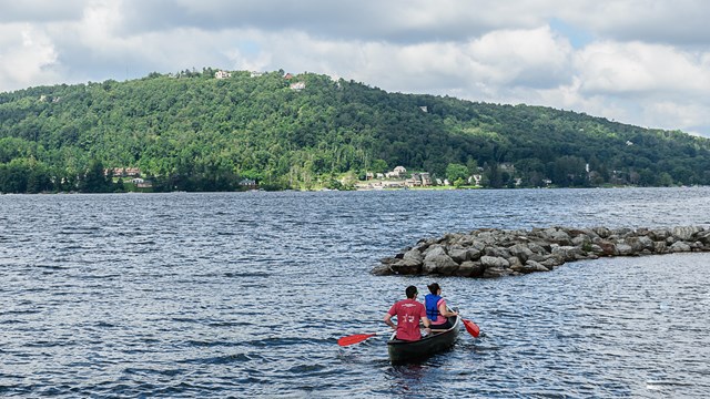 Two people paddling a canoe in a lake.