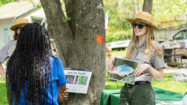 A park ranger showing a photograph of a fish to a visitor. 