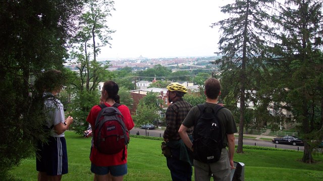 4 people looking at a city from a hilltop. 