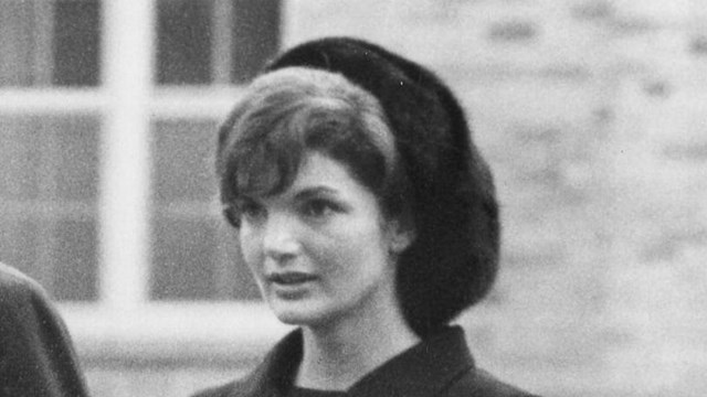 B&W photo of Jacquelin Kennedy with black suit and hat.