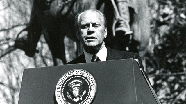 President Gerald Ford stands at a podium in front of a statue
