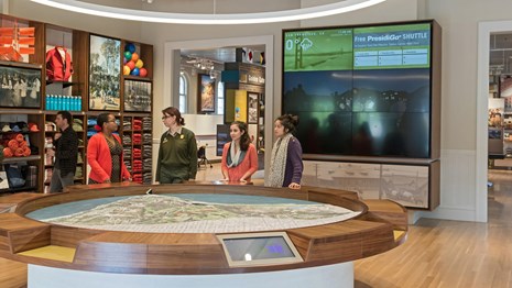 A ranger and visitors look at a 3-D map of the Presidio in the visitor center