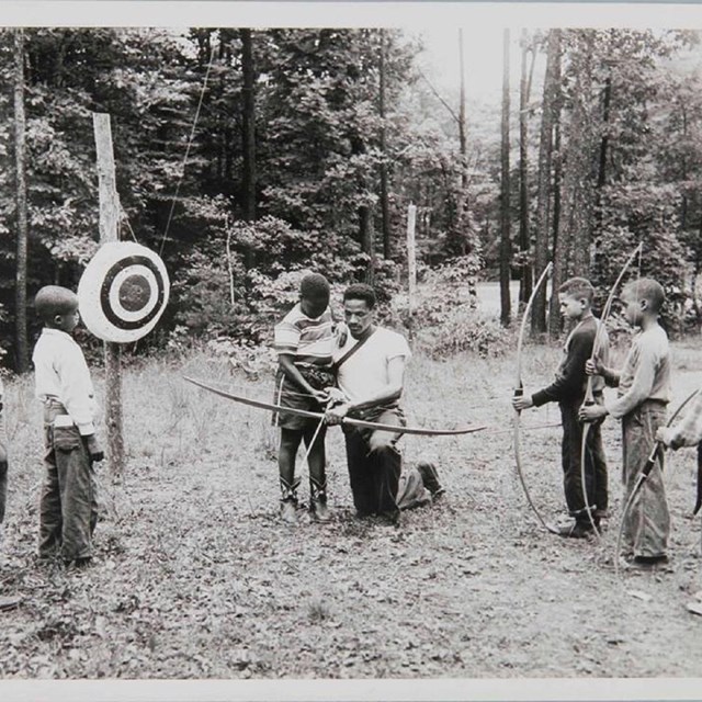 Young campers learning archery in a historic 1930s photo
