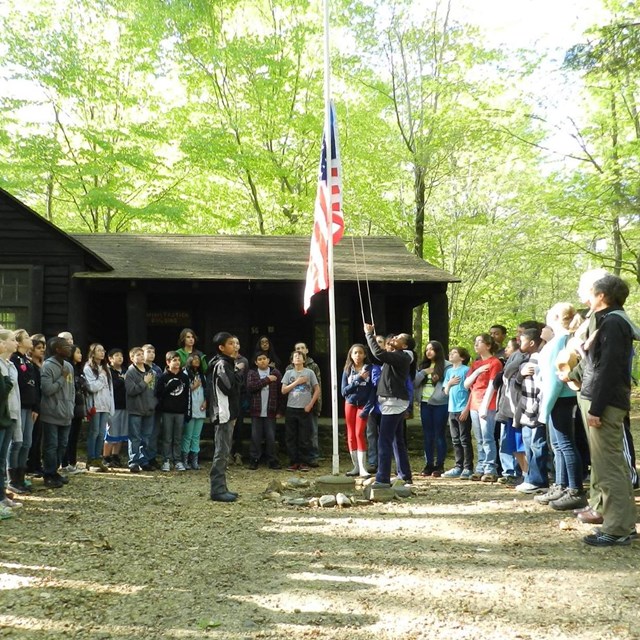 Large group of kids surrounded a flag pole