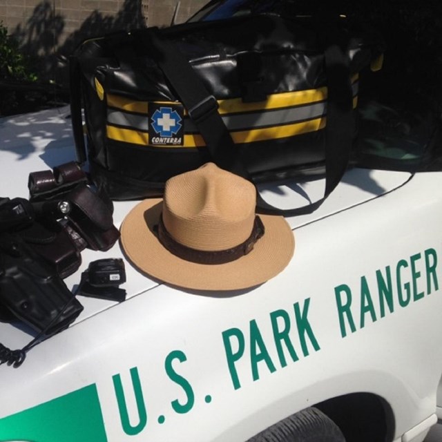A ranger hat and equipment laid out on the hood of a U.S. Park Ranger vehicle.