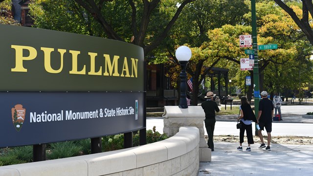 A ranger leads a pair of visitors past the Pullman site sign. 