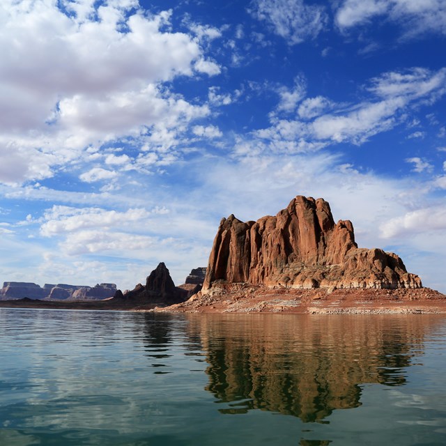 Symmetric sandstone butte reflected in calm water.