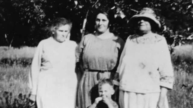 Black and white photo of three woman and a young boy in front of a tree