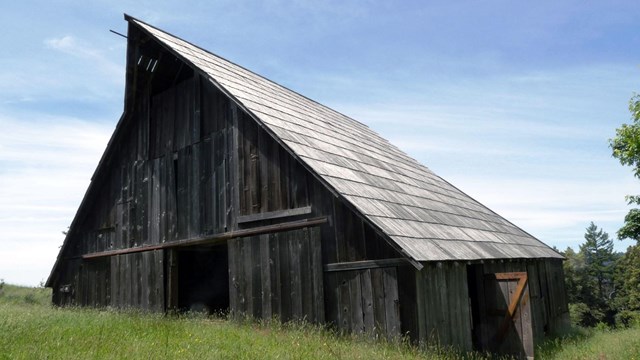 A large wood barn with a high peak roof