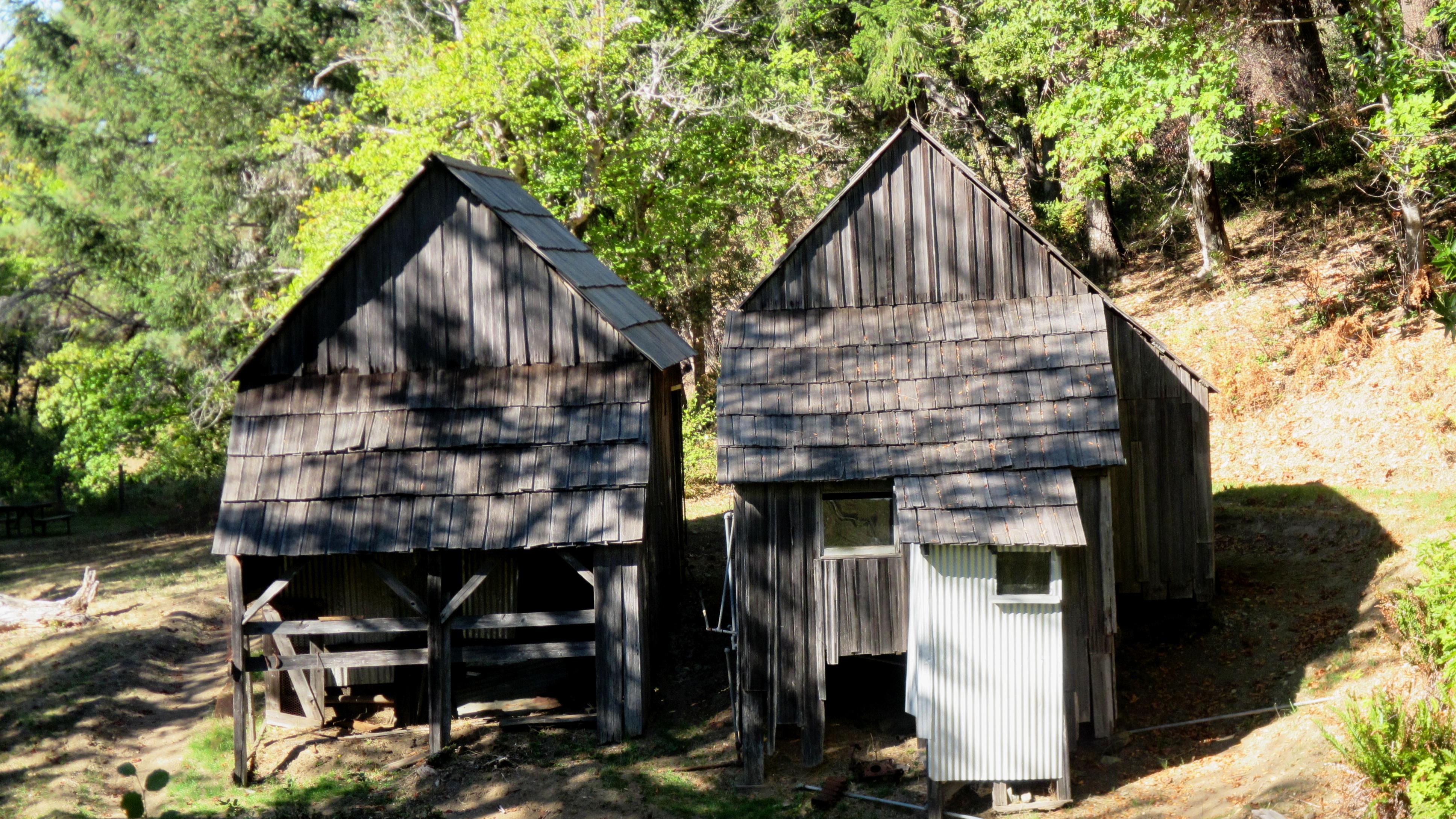19th century wooden buildings on a grassy slope.