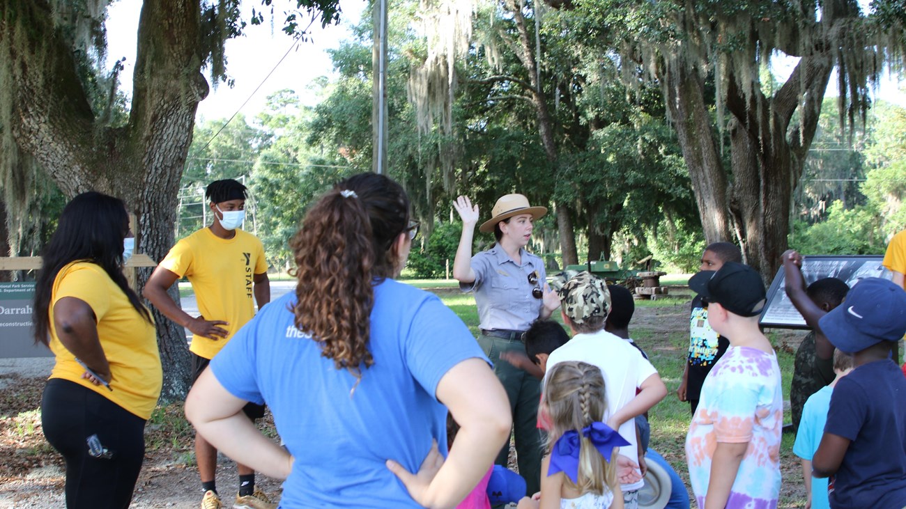 A ranger talking to students outside.