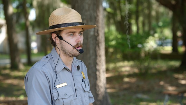 A ranger using a microphone to talk outside.