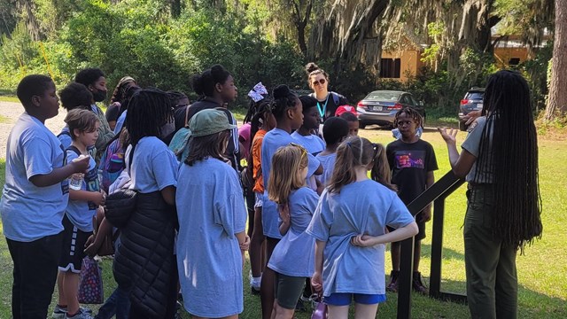 A ranger stands in front of a group of children.