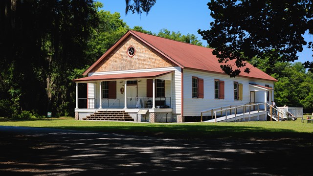 A single-story historic building with a red roof and porch.