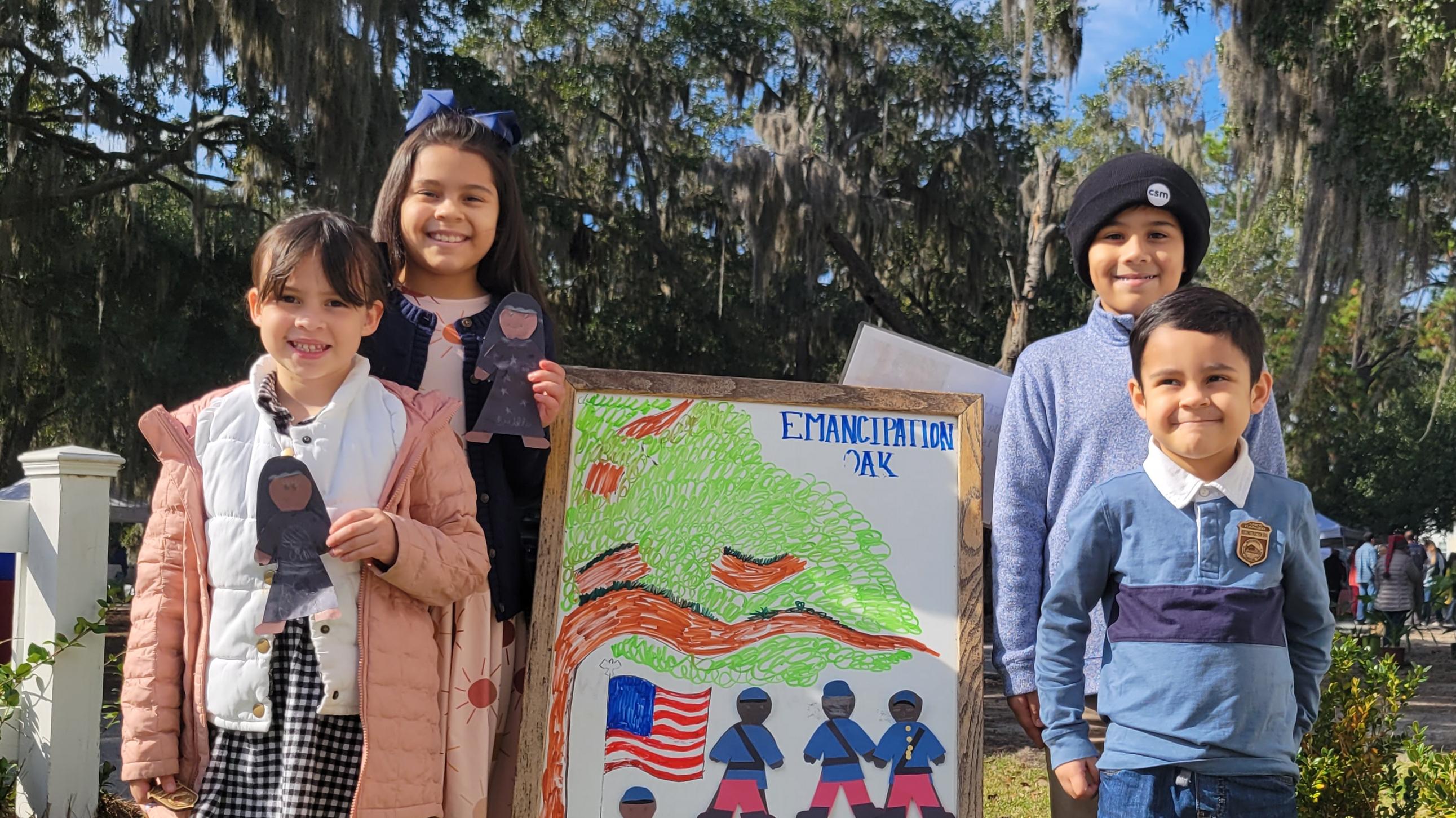 Four kids stand with paper nurses and soldiers they made wearing junior ranger badges.