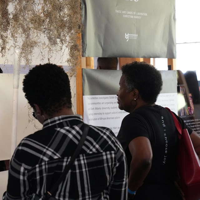 Two women read an exhibit about identity and land ownership.