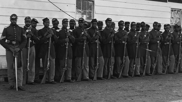 a black and white photograph of a group of uniformed African American Civil War soldiers.