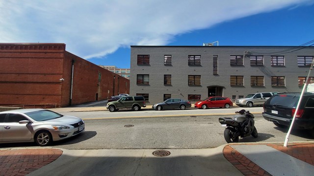 a photograph of a red brick and a gray brick warehouse building on a city street.