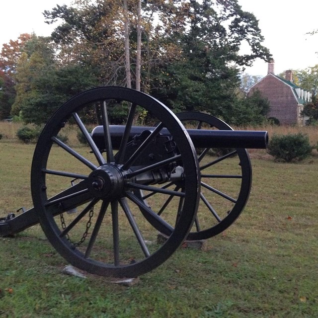 Civil War cannon in foreground, brick colonial house in background