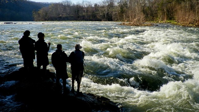 4 people standing on the bank of the flowing Greenbrier River, West Virginia